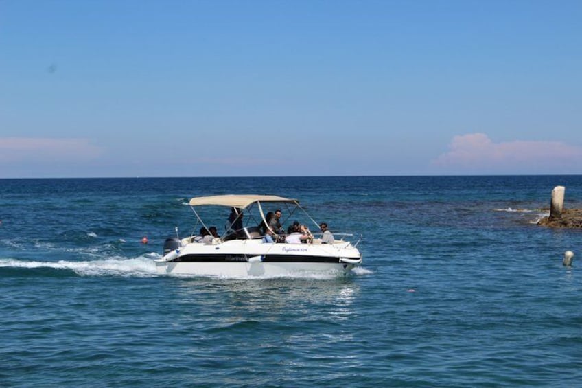 Ein weißes Schnellboot mit Verdeck bewegt sich über ein ruhiges Meer unter blauem Himmel. 2