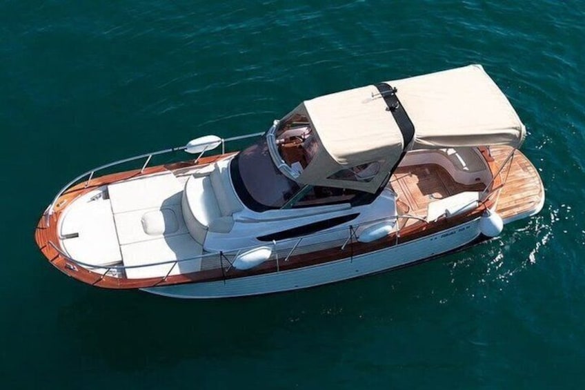 A boat with a covered seating area, a white cabin, and a wooden deck. 1