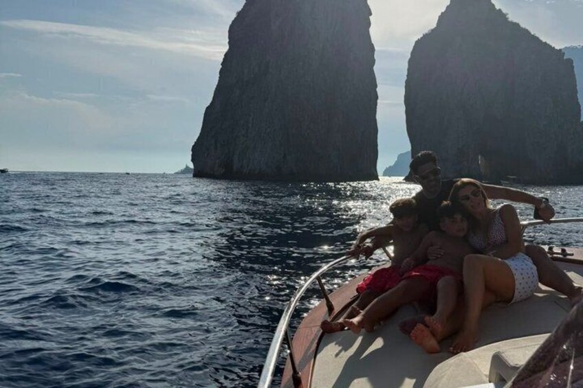 A boat with people on a clear day, surrounded by large rock formations in the water. 2
