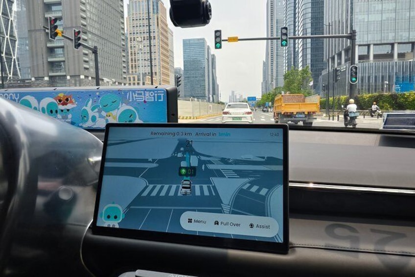 A car dashboard with a navigation screen displaying a traffic light ahead and a message indicating arrival in 12 minutes. 2