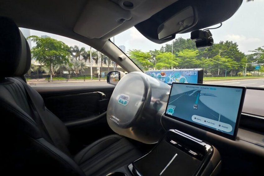 A car interior with a digital display, a steering wheel, and a view of the road outside. 4