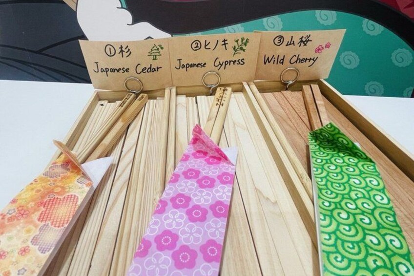 Bacchette di legno esposte con protezioni di carta colorata, recanti nomi giapponesi. 2
