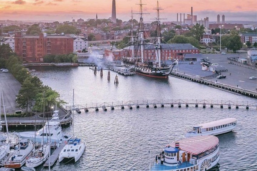 Een haven met een hoge mastboot, een stoomboot en verschillende kleinere bootjes. 2