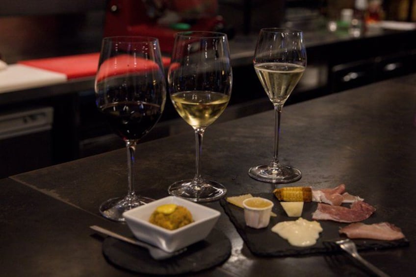 Une table avec trois verres à vin, un petit bol de sauce jaune et quelques tranches de viande. 5