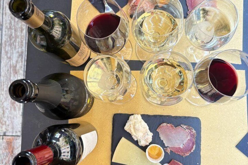 Et bord med vinflasker, glas, ost og kød. 5
