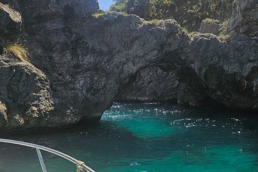 A rocky coastal landscape with a clear blue sea and a boat in the foreground. 1