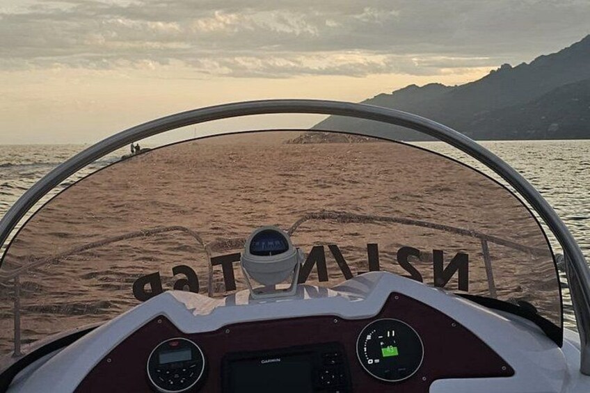 A boat's cockpit with a view of a beach and mountains in the background. 5