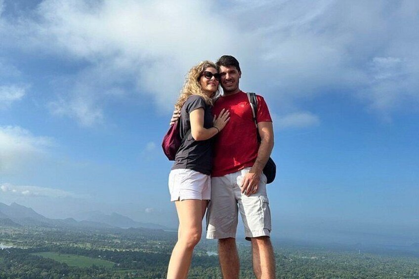 Two people embracing on a mountain top with a clear sky and a view of a valley below. 2