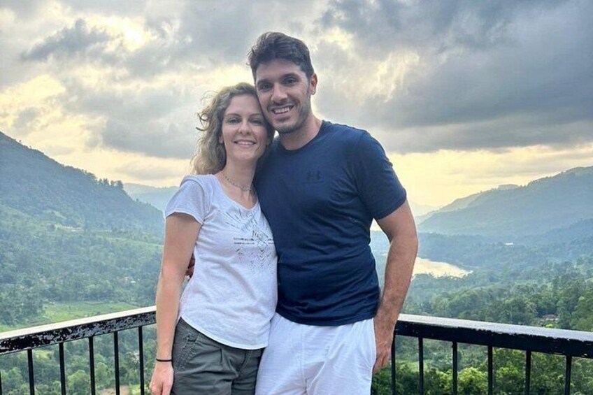 A couple standing on a balcony with a mountainous landscape in the background. 5
