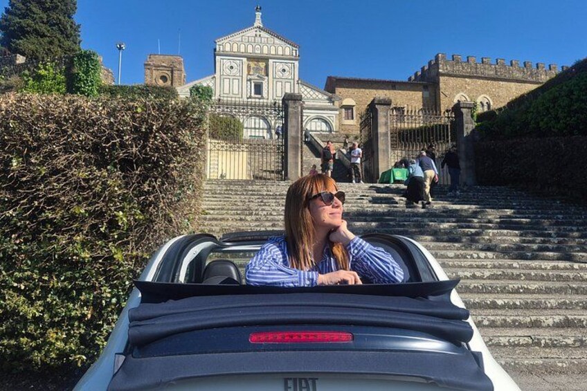 A person in a convertible driving down a set of stairs with a historic building in the background. 3