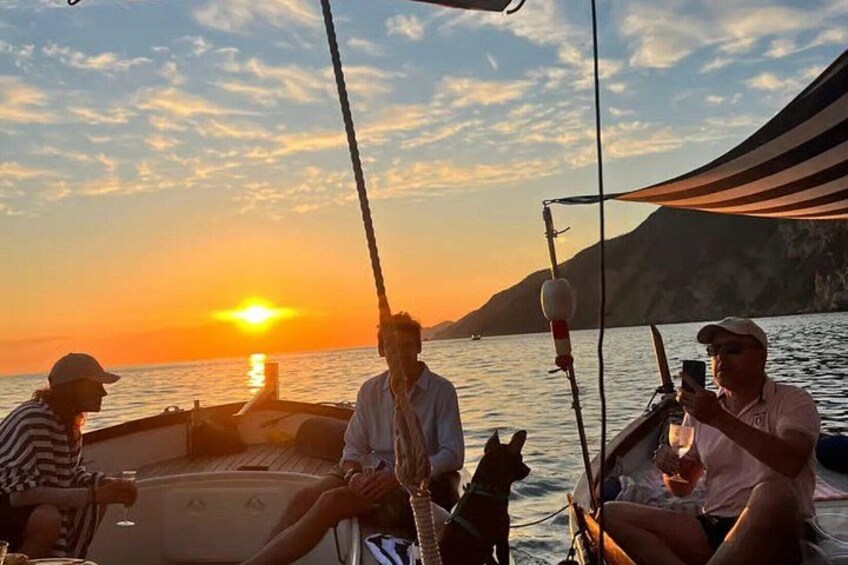 Solnedgang over vand med båd, mennesker og en hund. 2
