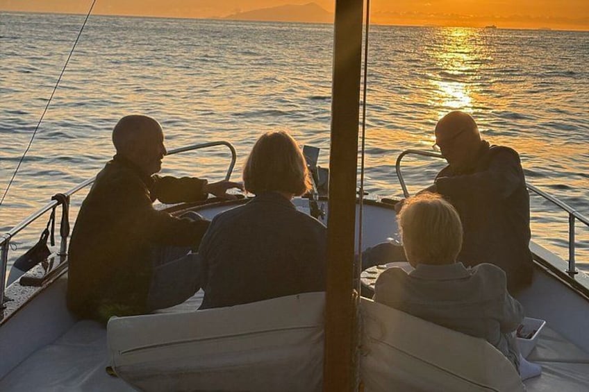 A boat with four people on a calm sea during sunset. 2