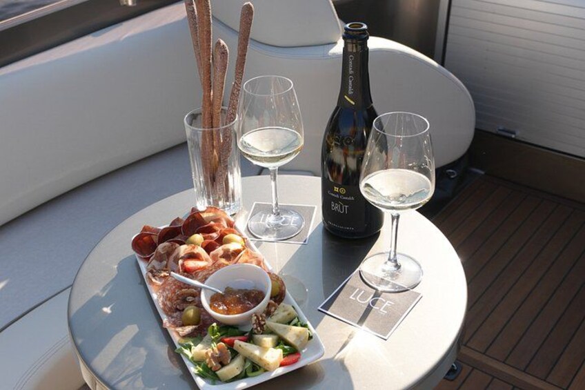 Une table avec une bouteille de champagne brut, deux verres, une assiette de hors-d'œuvre et un petit bol de sauce. 1