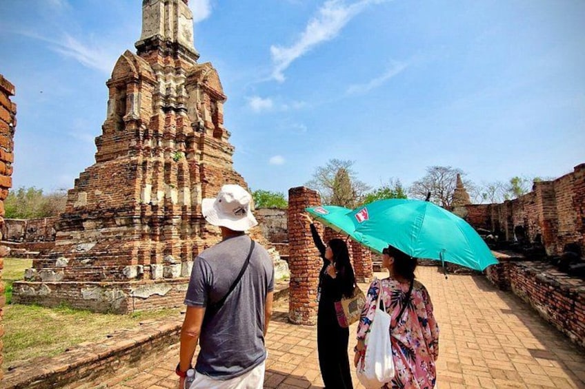 A historical brick structure with a central spire, a person holding a turquoise umbrella, and another person with a white bag. 5