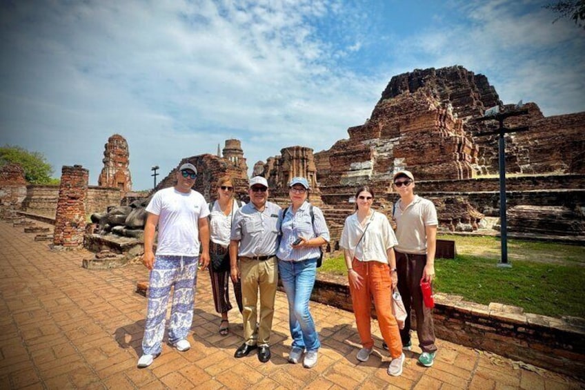 A group of people standing in front of ancient ruins with stone structures and a clear sky. 2