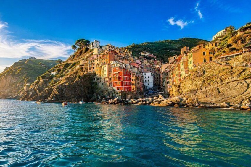 Un village côtier aux bâtiments aux couleurs vives, bordé par une mer d’un bleu limpide et des falaises rocheuses. 2
