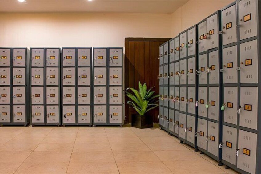 Een rij metalen lockers met nummers, een potplant en een houten deur op de achtergrond. 4
