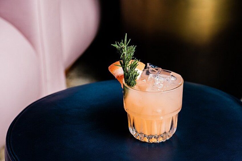 A glass of a pinkish beverage with a garnish on a dark blue table. 5