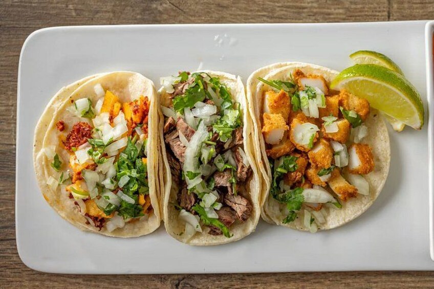Three tacos with different fillings on a white plate. 4