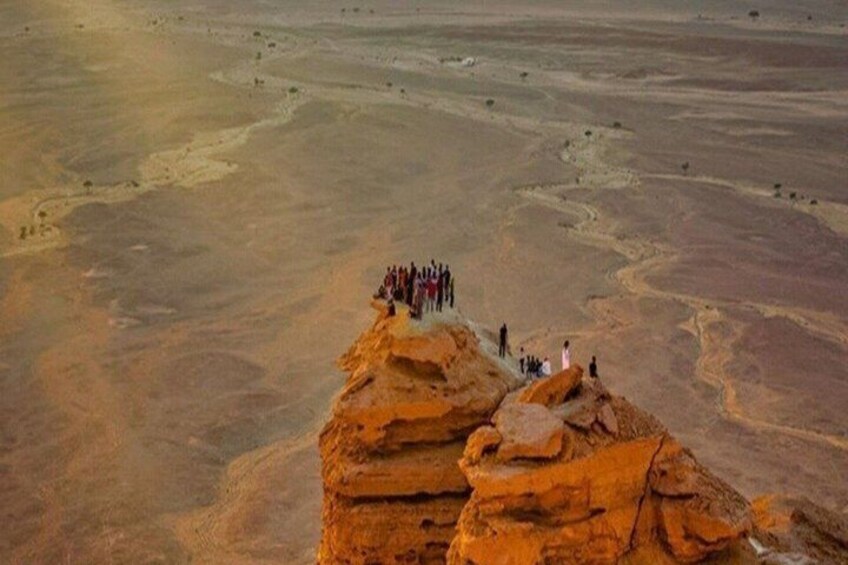 A group of people standing on a rocky outcrop in a vast desert landscape. 4