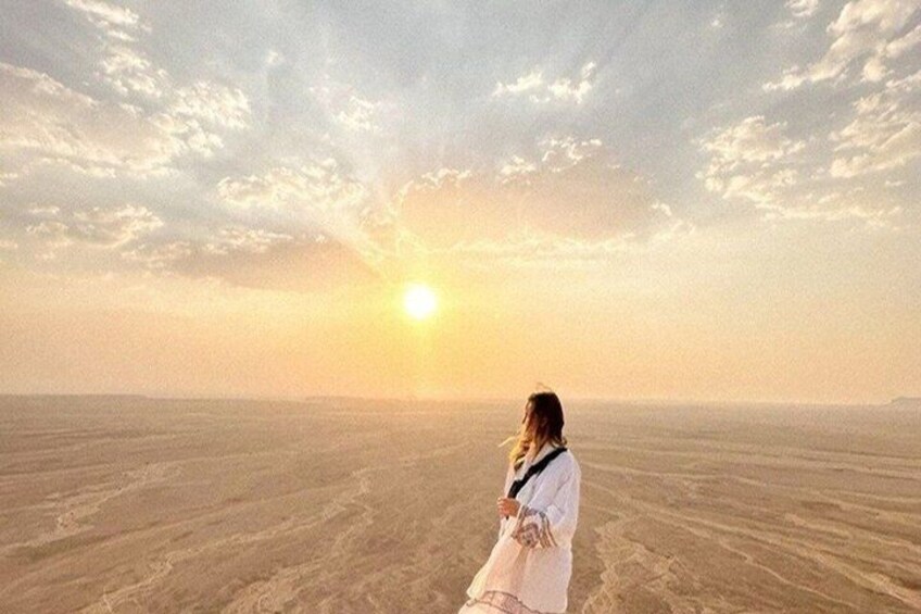 A person standing in a vast desert landscape with a sunset in the background. 3