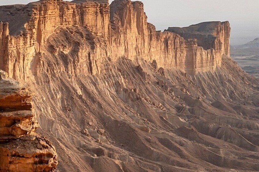 A rugged desert landscape with prominent sandstone cliffs and a vast, arid terrain. 2