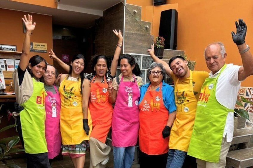 Un groupe de personnes portant des tabliers posent pour une photo dans une cuisine. 1