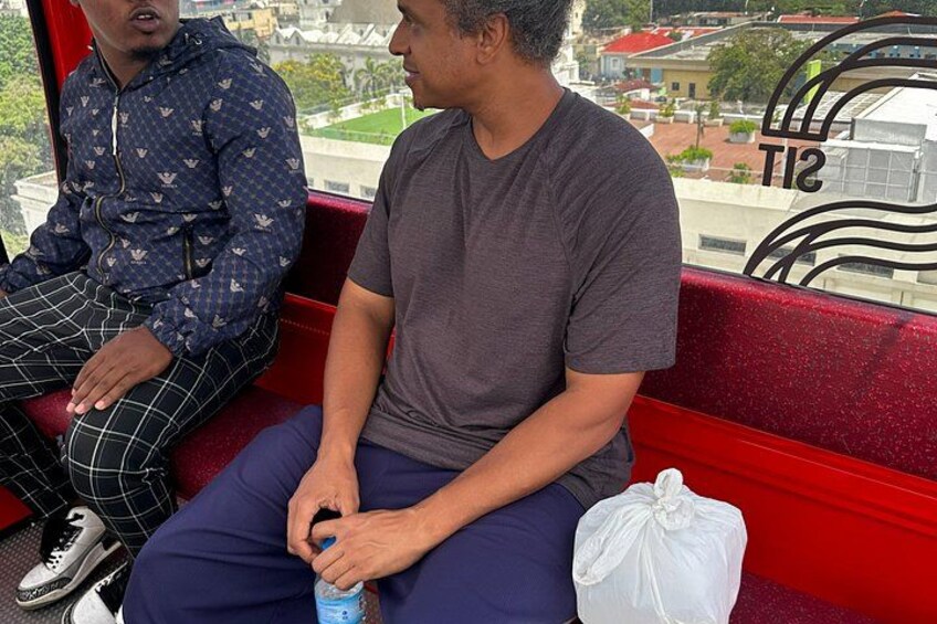 Deux hommes sont assis sur un banc rouge, avec une vue sur la ville en arrière-plan. 2