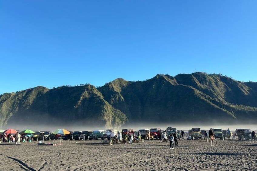 Une plage avec des gens et des tentes, et des montagnes en arrière-plan. 5