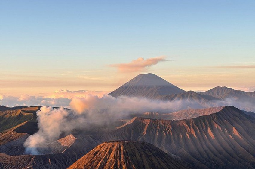 Paisaje volcánico con una montaña destacada, crestas y vapor elevándose del terreno. 1