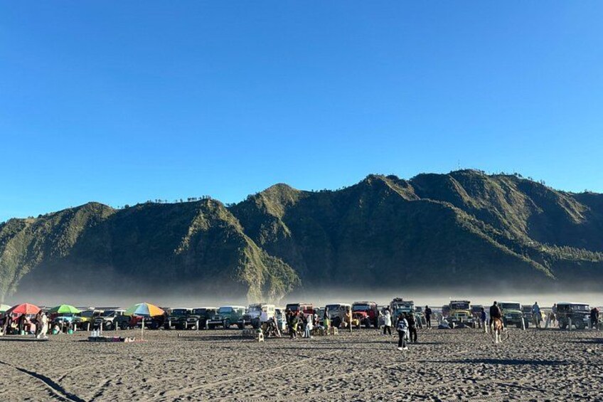 A beach with people and vehicles, and mountains in the background. 5