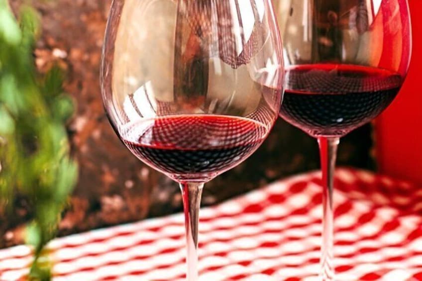 Two wine glasses with red liquid on a checkered tablecloth. 3