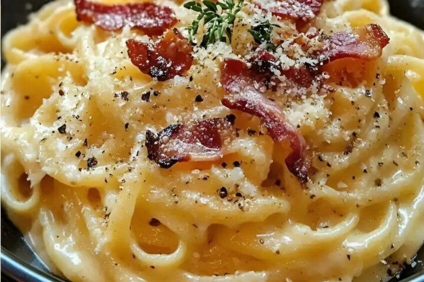 A plate of pasta with bacon and herbs. 4