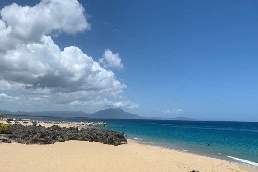 A beach with clear skies, calm waters, and distant mountains. 5