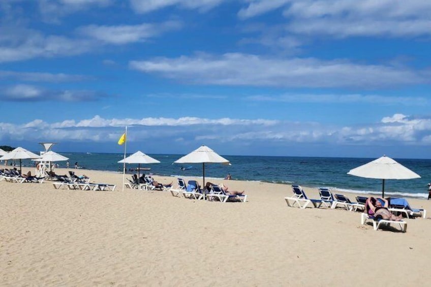 A beach with sun loungers and umbrellas under a clear sky. 4