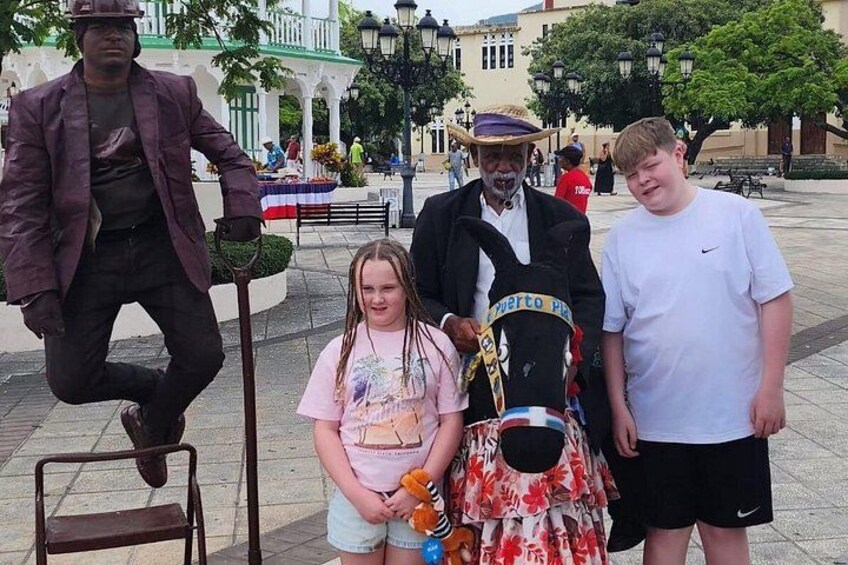 A statue of a man in a suit, a child in a floral dress, and a man in a hat. 3