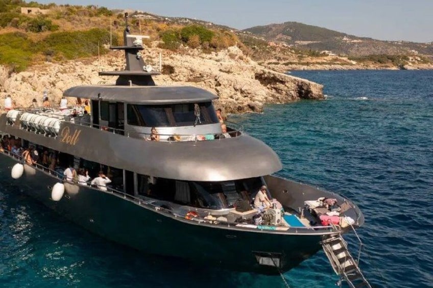 Un barco grande amarrado a una costa rocosa con agua azul cristalina. 2