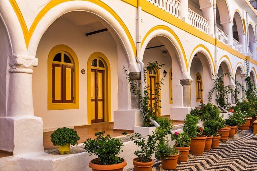 Un edificio con ventanas y puertas de marco amarillo, paredes blancas y suelo de baldosas. 2