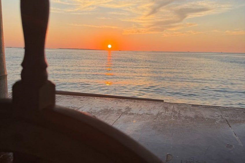 Un tramonto sull'oceano, con la sagoma di una persona in piedi su un molo. 5