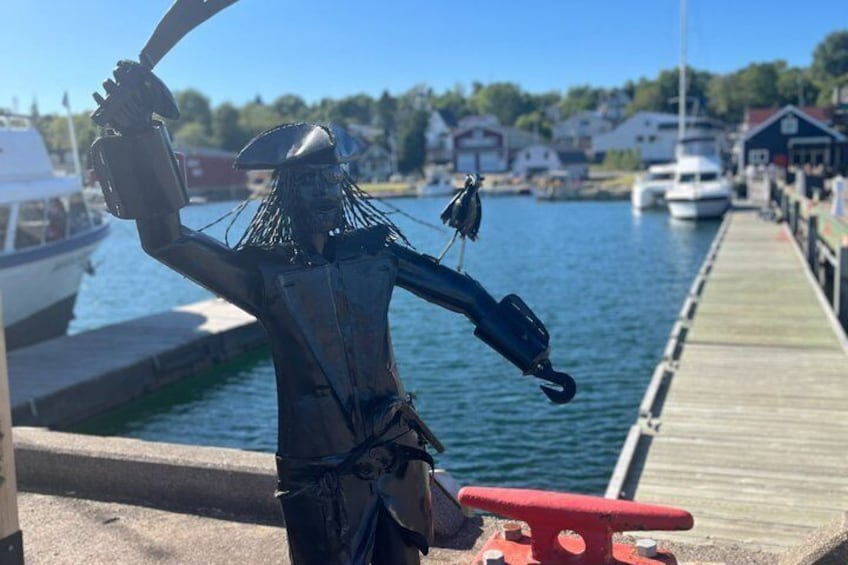 Una statua di un pirata con un gancio, un uccello e una nave sullo sfondo. 2