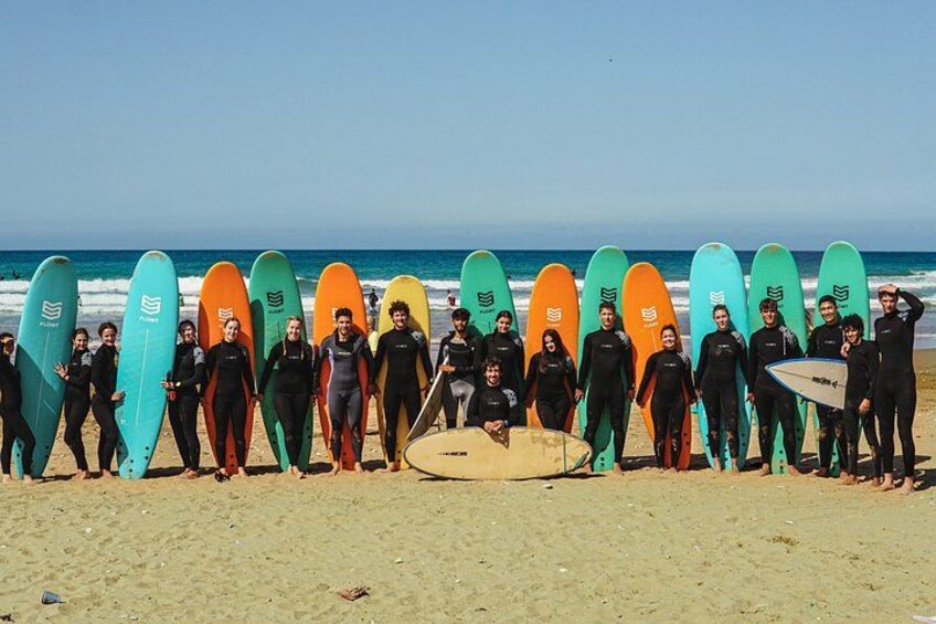 A group of surfers on a beach with surfboards lined up. 3