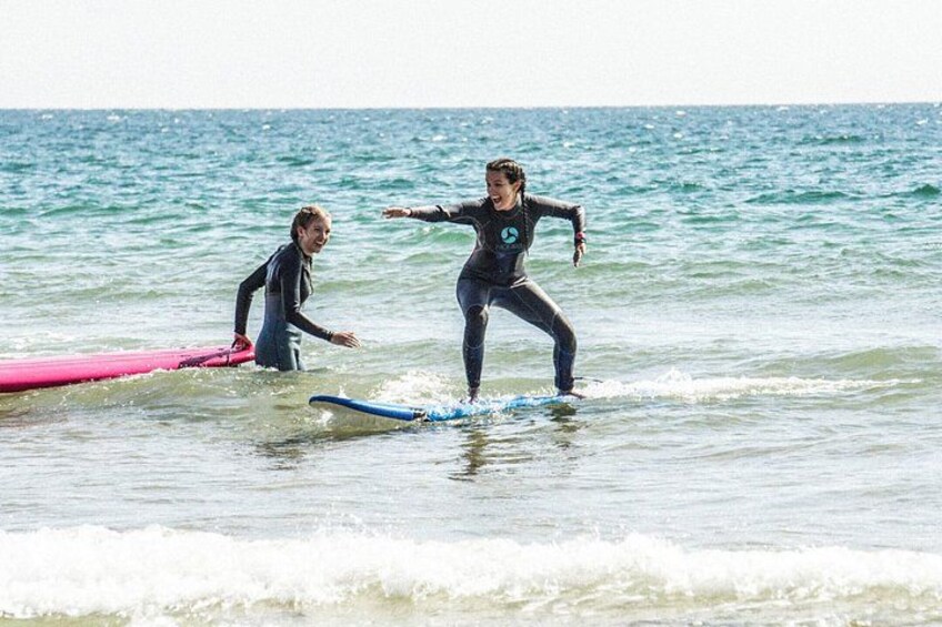 Two people in wetsuits surfing in the ocean. 1