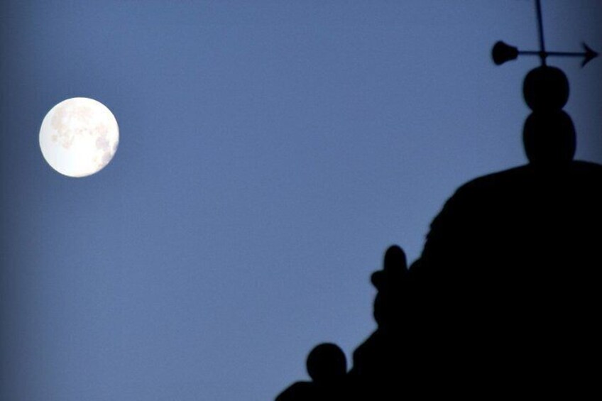 A full moon in the sky, a silhouette of a person with a hat, and a wind vane on a hill. 5
