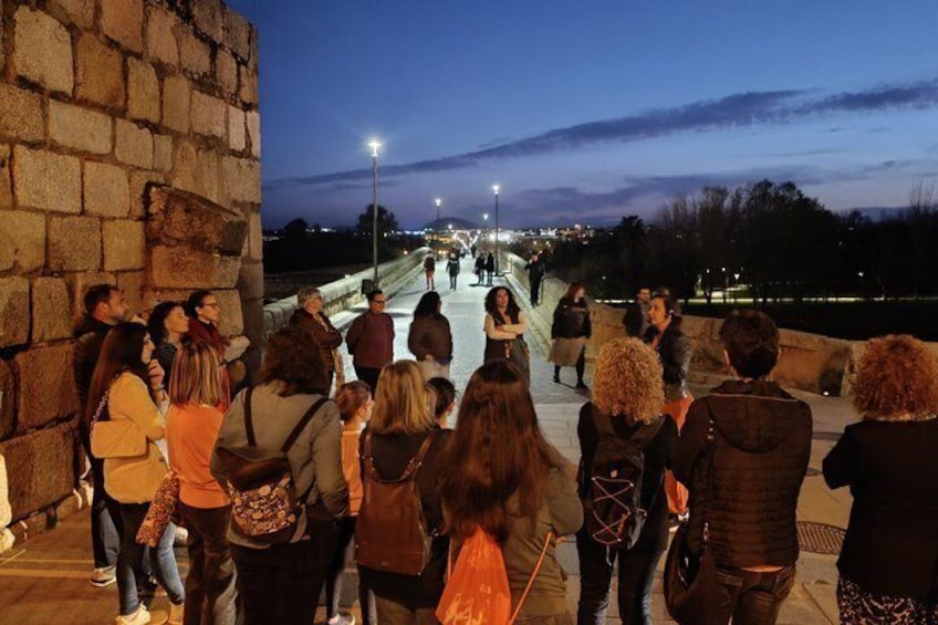 A group of people standing on a bridge at dusk. 3