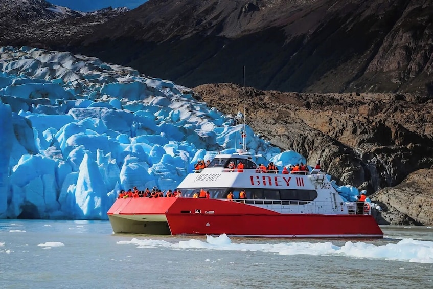 A boat named 'GREY III' with passengers wearing orange life jackets, navigating a glacier. 1