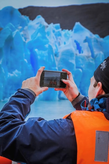 A person taking a photo of a glacier. 4
