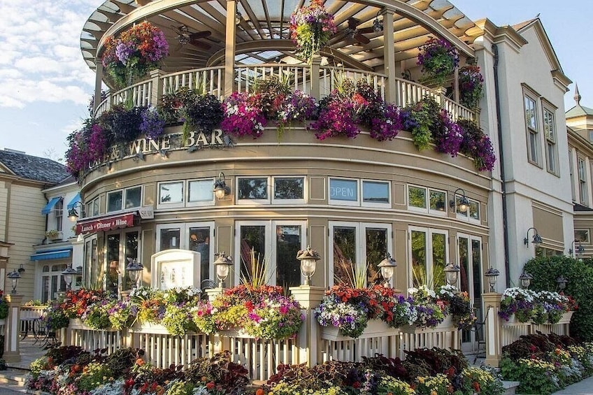 A building with a sign reading 'WINE BAR' and a balcony with hanging flower baskets. 3