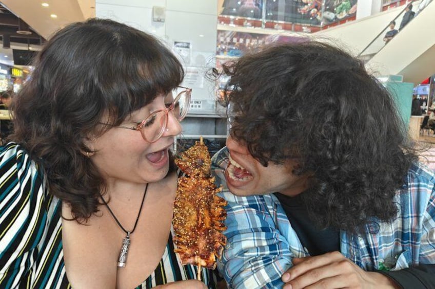 Two people eating at a food stall in a shopping mall. 2