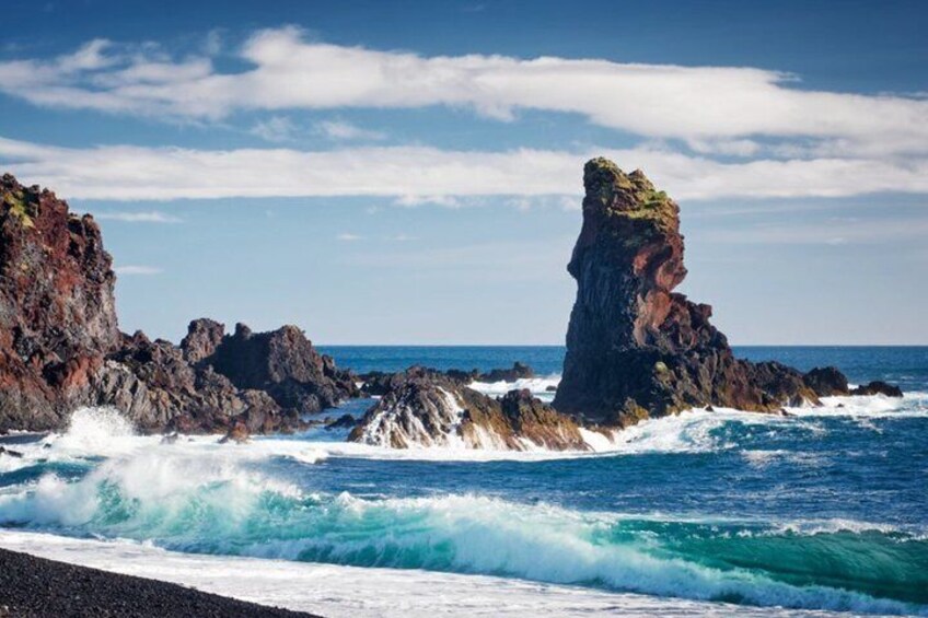 A rocky coastline with waves crashing against the shore and a prominent rock formation. 2