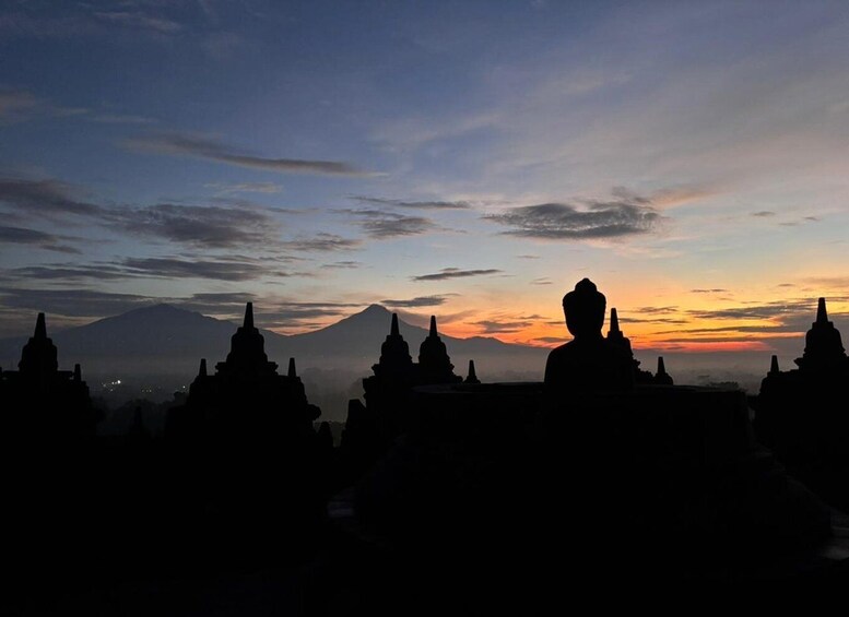 A silhouette of a person in meditation against a sunset sky, with a mountain and temple structures in the background. 4